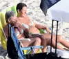 Claudia Rodrigues curte praia e dá beijão em companheira no Rio