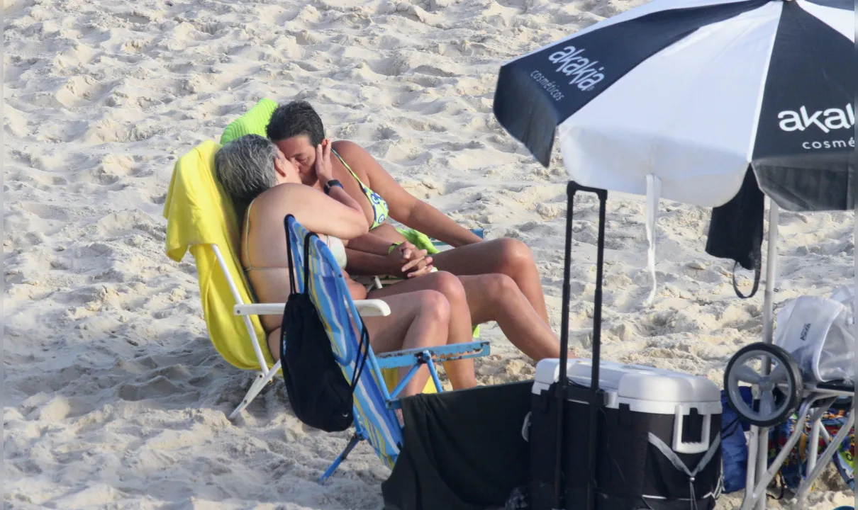 Claudia Rodrigues curte praia e dá beijão em companheira no Rio